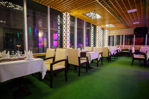 un comedor con mesas y sillas blancas en HOTEL BLUE BIRD en Dhaka