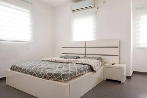 a white bedroom with a white bed and windows at Oַ&O Group-Amazing APT Bat-Yam 3 Min Walk To Beach in Bat Yam