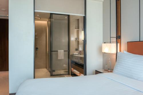 a bedroom with a white bed and a shower at Radisson Blu Hotel & Spa, Nashik in Nashik