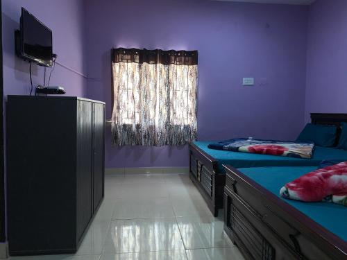 um quarto com 2 camas, uma televisão e uma janela em Pinetree Residency em Kodaikānāl