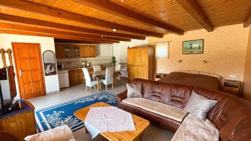 a living room with a leather couch and a kitchen at Magyar Apartmanházak I-III. in Zalakaros