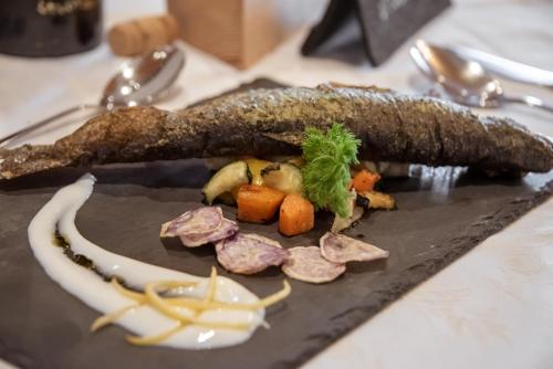 a piece of fish on a plate with meat and vegetables at Naturhotel Waldheim in Anterivo