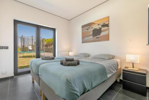 a bedroom with a large bed and a large window at Casa Amizade in Aljezur