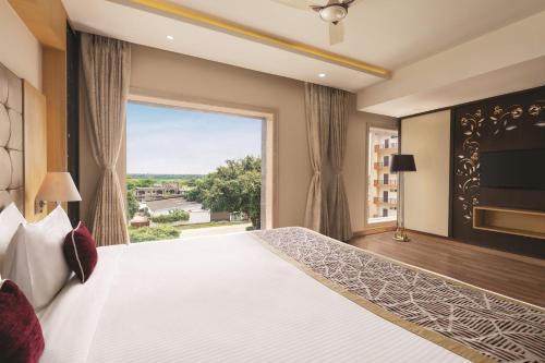 a bedroom with a large bed with a large window at Ramada by Wyndham Varanasi Katesar in Chandauli