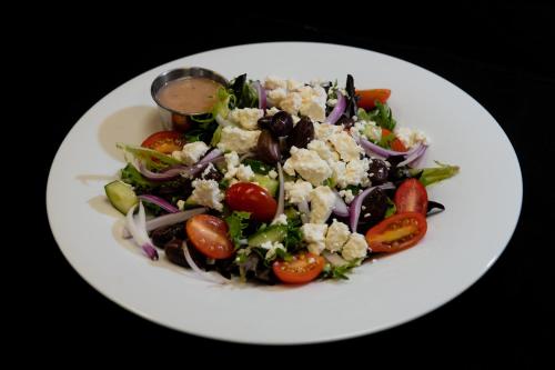 a white plate with a salad with tomatoes and vegetables at Holiday Inn Newark International Airport in Newark