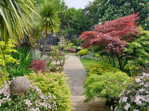 a wooden path through a garden with flowering plants at Tropical Garden Oasis Rooms in Birmingham