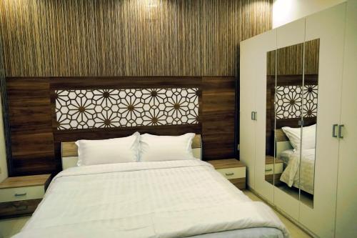 a bedroom with a large white bed and a mirror at فضة تالا للشقق المخدومة 2 in Buraydah