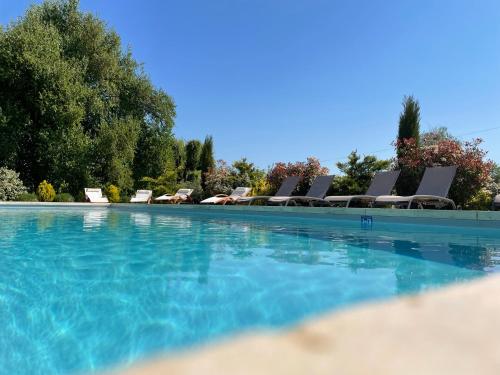 a swimming pool with chairs and a bunch of water at Au Soleil d'Or in Pontaubert