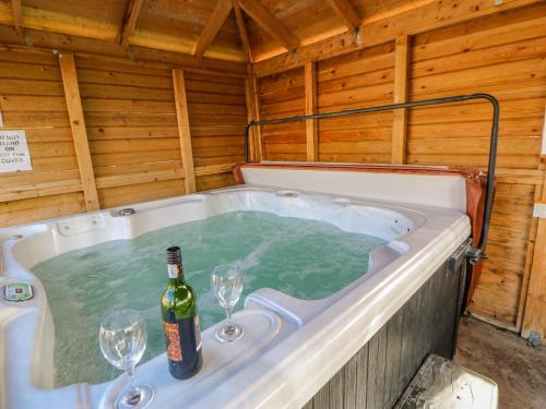 a hot tub with a bottle of wine and two glasses at Burns Cottage in Barnard Castle