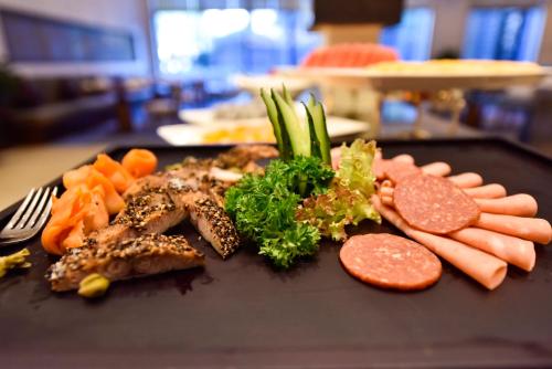 a black plate of food with meat and vegetables on it at Howard Johnson Neodalle Resort Zhangjiajie in Zhangjiajie