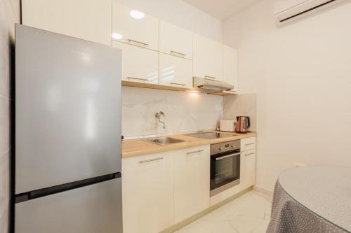 a white kitchen with white cabinets and a sink at Soprani in Klis