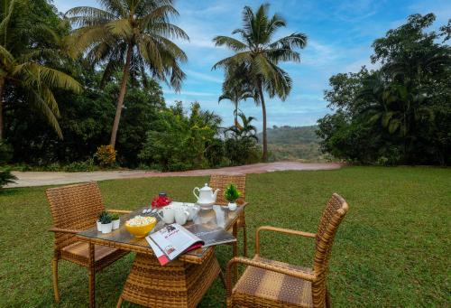 a table with two chairs and a table with food on it at SaffronStays Meadowbrook, Panvel - pet-friendly villa near Karnala Bird Sanctuary in Āpta