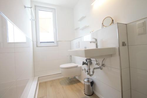 een witte badkamer met een wastafel en een toilet bij Haus Barbara - Schwimmbad und Sauna im Haus-Whg 11 in Grömitz
