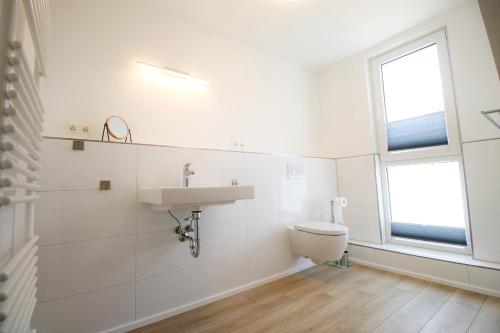 uma casa de banho branca com um lavatório e um WC em Haus Barbara - Schwimmbad und Sauna im Haus-Whg 12 em Grömitz