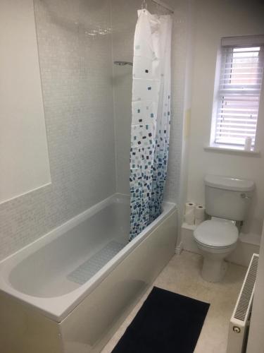 Un baño blanco con bañera y inodoro. en Beautiful 2 bed apartment, en Grantham