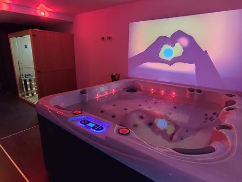 ein Badezimmer mit einer Badewanne mit einem Bildschirm mit einem Herz darauf in der Unterkunft AVEC TOI suite spa in Barlin