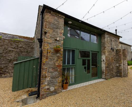 a green door on the side of a brick building at Stay Barrow Blueway - The Stables in Monasterevin
