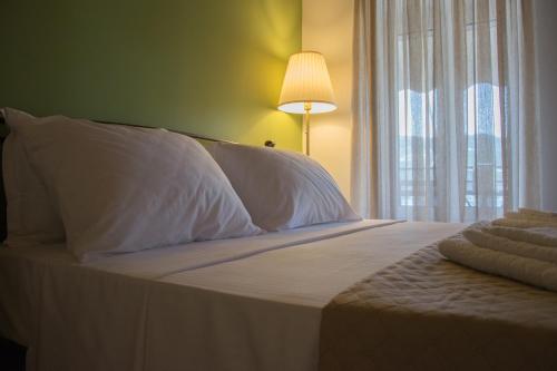 a bed with white sheets and a lamp and a window at Stonehouse with wonderful seaview in Samos