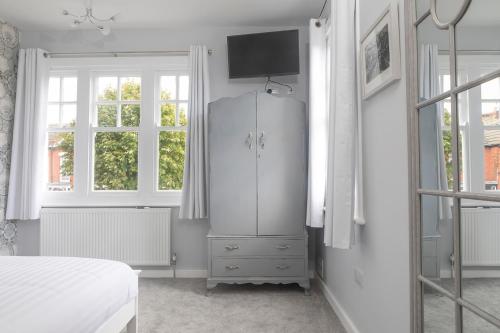 a white bedroom with a dresser and a bed at The Sleep-Inn Hare B&B in Herne Bay