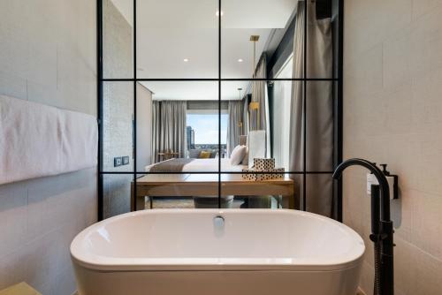a bath tub in a bathroom with a bedroom at InterContinental Perth City Centre by IHG in Perth