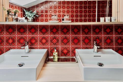 2 lavabos blancos en un baño con azulejos rojos en Ferienwohnung ChiemseeAlpenBlick, en Breitbrunn am Chiemsee