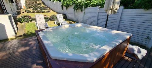 a hot tub sitting on a deck with a bench at 3 Lagoon Getaways in Southbroom