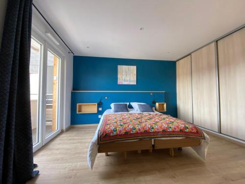 een slaapkamer met blauwe muren en een groot bed bij L'Escampette, superbe appartement avec terrasse in Gérardmer