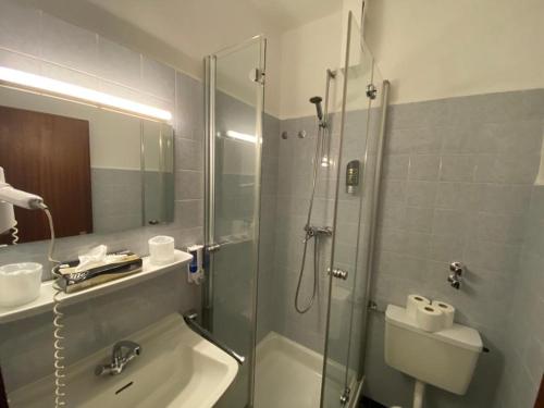 a bathroom with a shower and a sink and a toilet at Taverna Hotel Römerkrug in Hannover