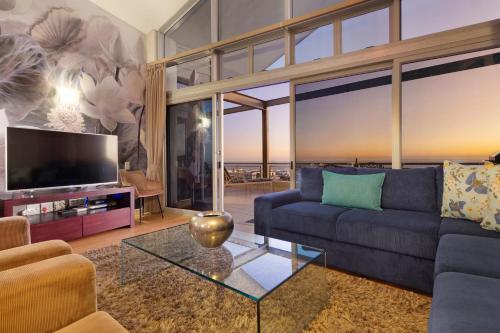 a living room with a couch and a tv at Seaside Village Penthouse F23 by HostAgents in Cape Town