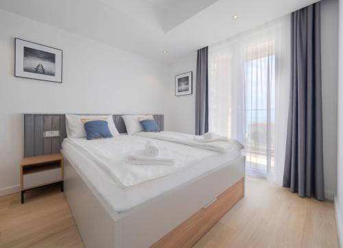 a white bed in a room with a large window at Horizon-One bedroom apartment with pool Jane in Becici