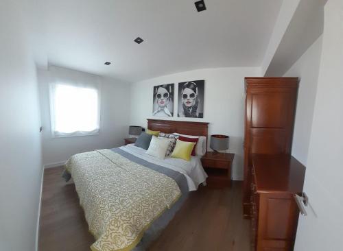a white bedroom with a bed and a window at Piso El Acantilado in Bueu
