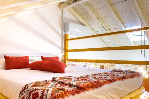 łóżko z czerwonymi poduszkami w pokoju w obiekcie Lavrio stone house 5 min from the centre/port w mieście Lawrio