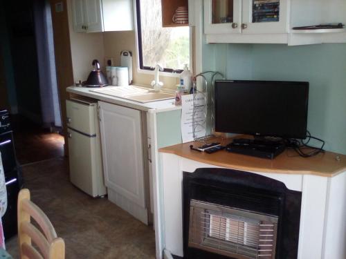 a kitchen with a desk with a computer monitor on it at River Views Dog friendly caravan 3 bedrooms in Rye