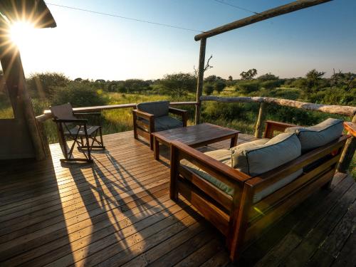 a wooden deck with a table and chairs on it at South Okavango - Omogolo Hideaways in Rammu
