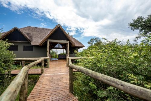 a wooden walkway to a house with a roof at South Okavango - Omogolo Hideaways in Rammu