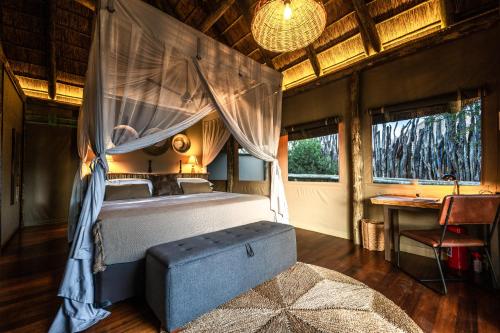 a bedroom with a bed with a canopy and a table at South Okavango - Omogolo Hideaways in Rammu