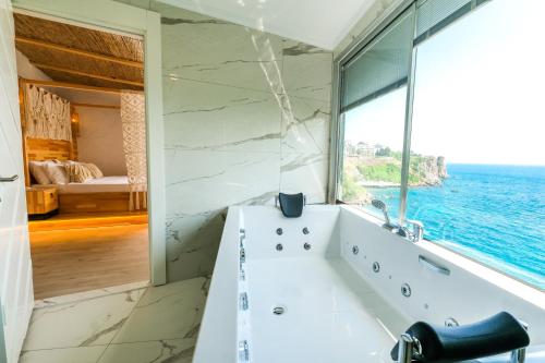 a bathroom with a tub and a large window at Bilem Hotel Beach & Spa in Antalya