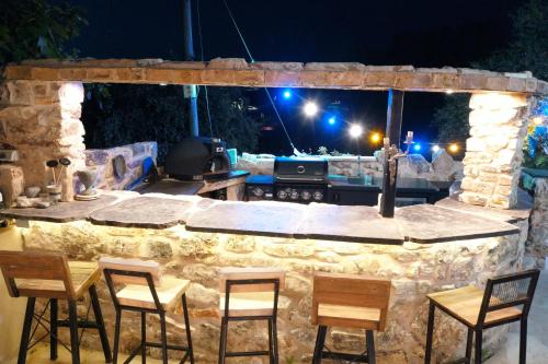 an outdoor bar with chairs and a stone wall at night at לאורה in Umm el Shuf