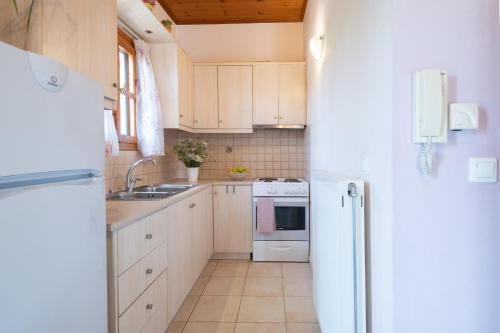 a kitchen with white cabinets and a sink and a refrigerator at Studio Dionphaie - Διόνφαιη in Pylos