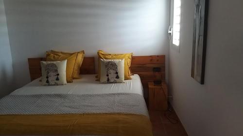 a bedroom with a bed with yellow pillows at VILLA TOCADE in Saint-François