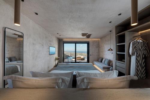 a room with a bed and chairs and a television at North Santorini - A Luxury Spa Hotel in Pirgos