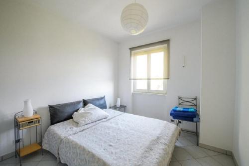 a white bedroom with a bed and a window at Diana Villa in Oggebbio