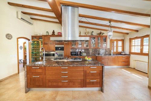 a large kitchen with wooden cabinets and a large island at Villa Plomer Serra in Playa de Muro