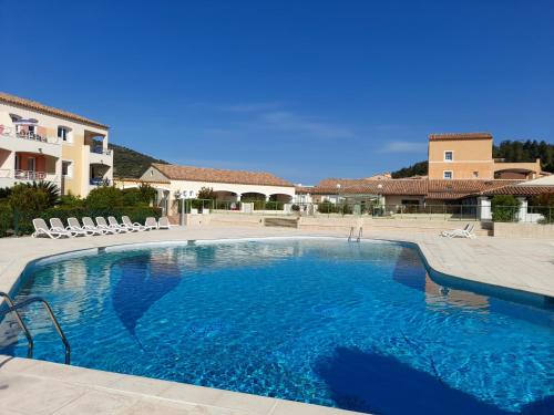 uma grande piscina com cadeiras e uma casa em Les Issambres, appartement pour quatre personnes em Roquebrune-sur-Argens