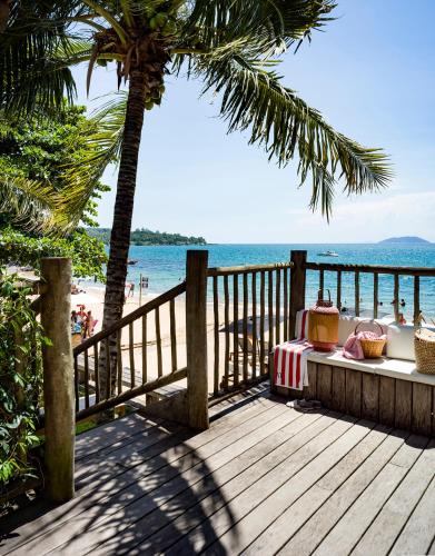 a wooden deck with a table and a view of the beach at TW Guaimbê Exclusive Suítes in Ilhabela