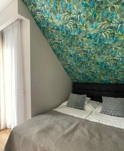a bedroom with a bed with a painting on the wall at Panoráma Apartmanház in Balatonfüred