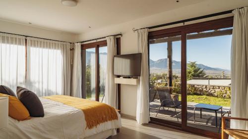 um quarto com uma cama e uma porta de vidro deslizante em La Madrina Apart Hotel em Tafí del Valle