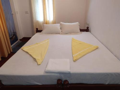 białe łóżko z 2 żółtymi poduszkami w obiekcie Marari Felix Beach Homestay w mieście Mararikulam