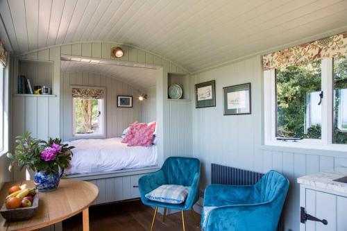 a small room with a bed and two blue chairs at Little Idyll shepherds hut in Chester