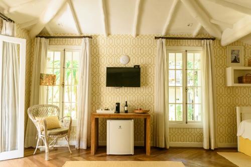 a room with a bed and a table and windows at TW Guaimbê Exclusive Suítes in Ilhabela